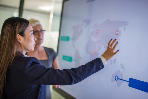 People in front of a smart board managing enterprise spend across multiple entities with Payhawk